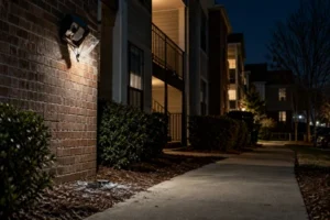 A dim apartment walkway shows exterior lighting and building access.